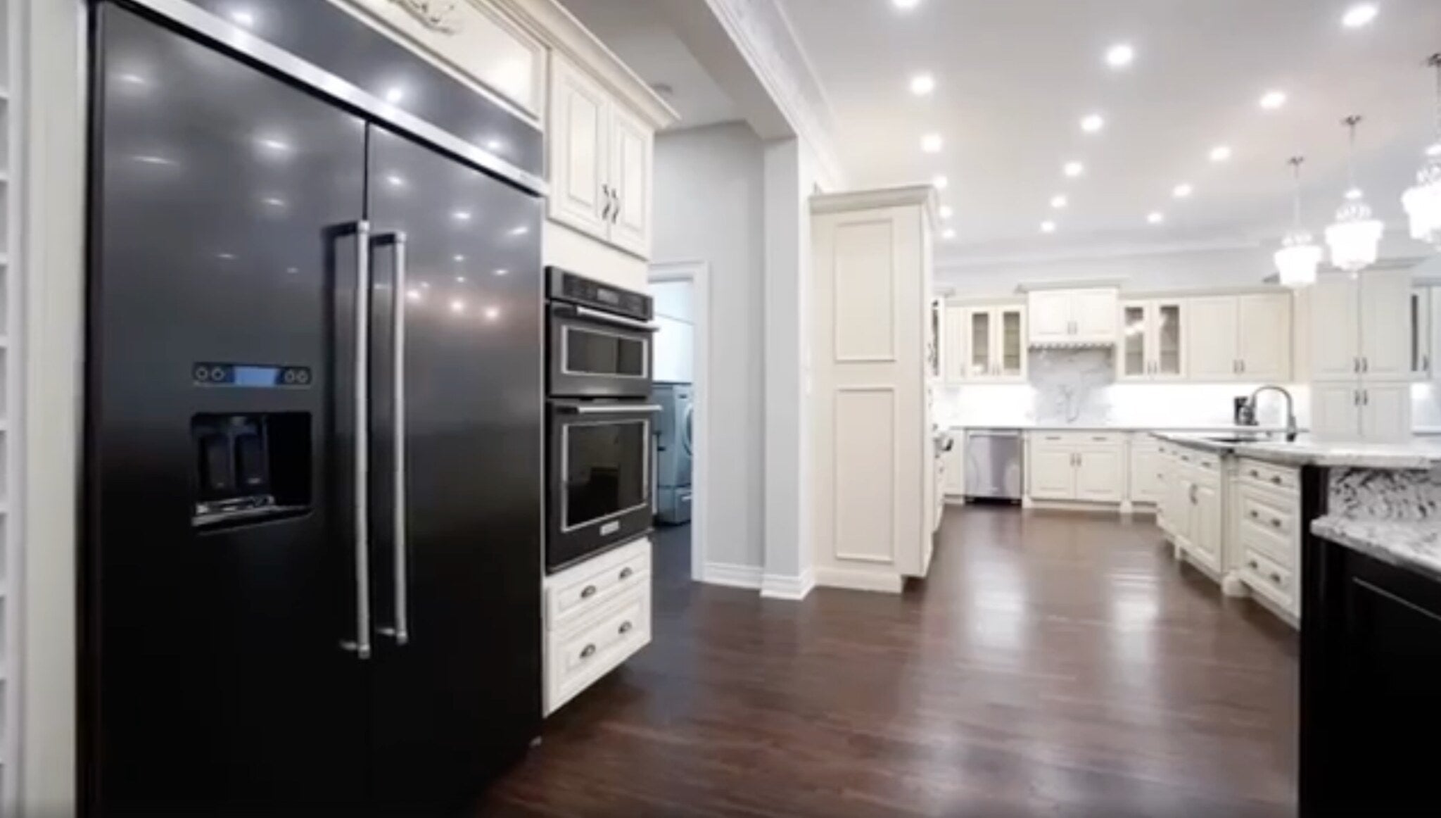Completed traditional white kitchen with dark appliances, a large island and layered cabinetry
