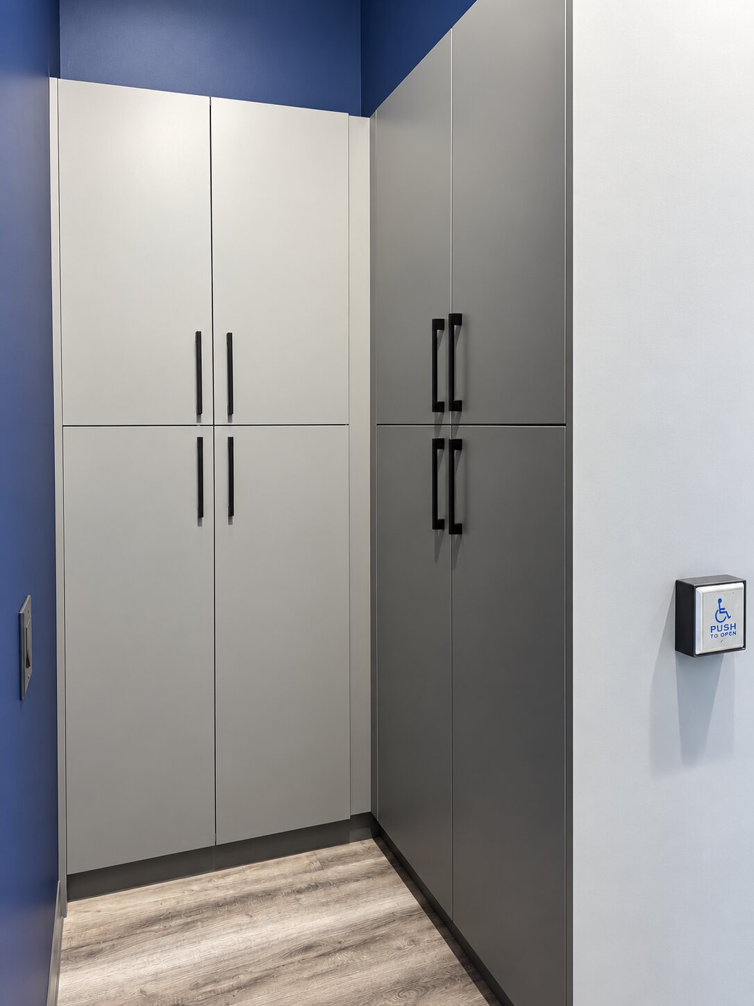 Full-height two-tone frameless storage cabinetry in white and charcoal with black bar pulls