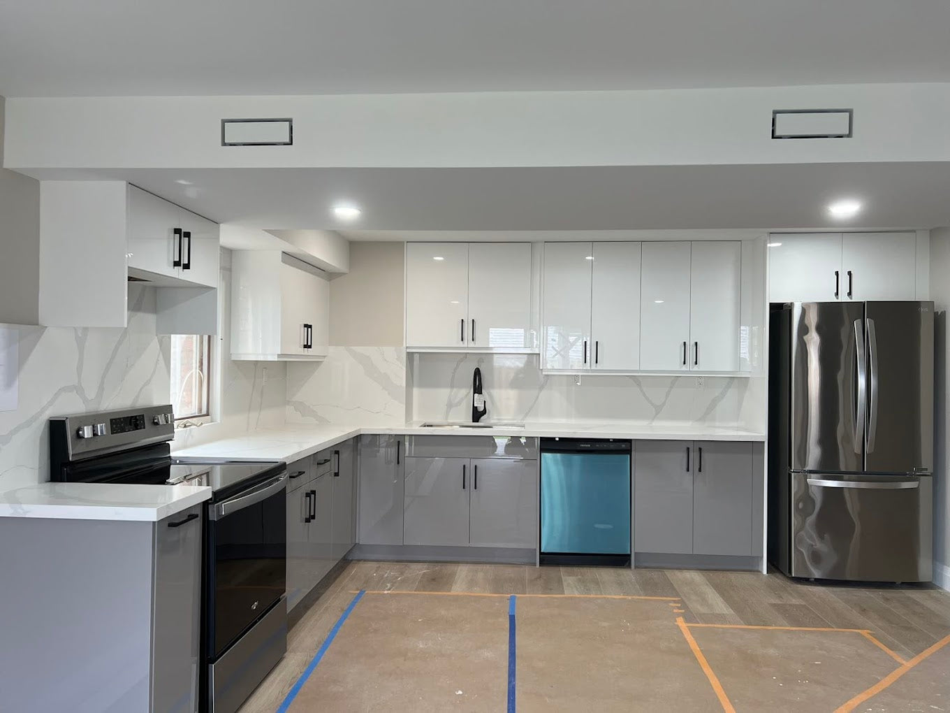 High-gloss two-tone kitchen with white upper cabinetry, grey lower cabinetry and full-height stone surfaces