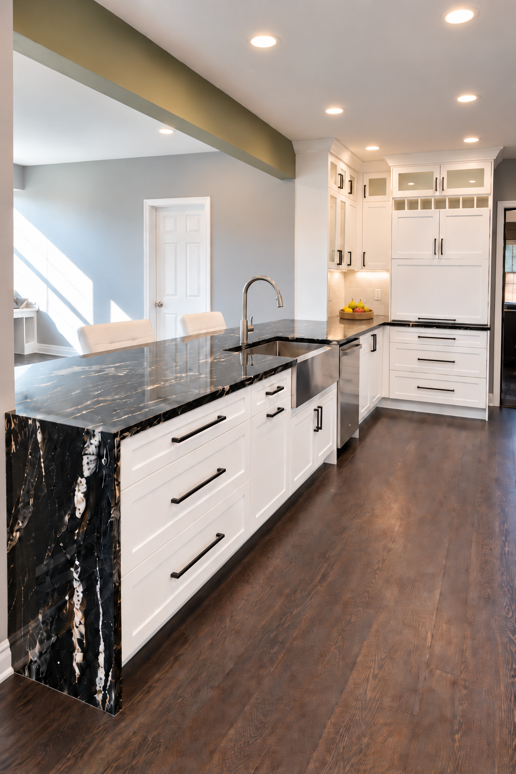 White Shaker kitchen with a polished black waterfall countertop, apron-front sink and brass hardware