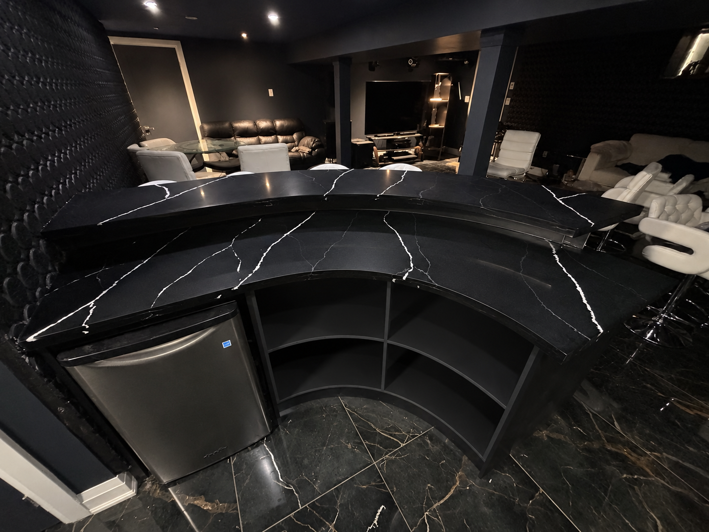 Curved black countertop and dark cabinetry in a completed commercial bar area